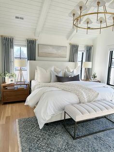 a large white bed sitting in a bedroom next to two windows