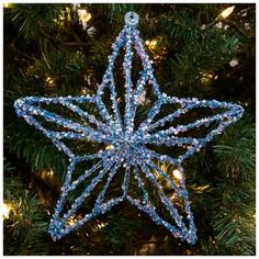 a blue star ornament hanging from a christmas tree