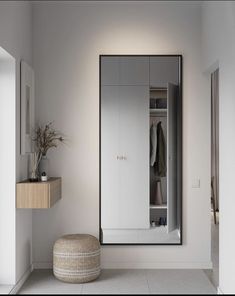 an empty room with a large mirror on the wall next to a stool and coat rack