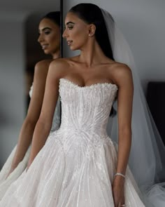 a woman in a wedding dress standing next to another woman wearing a bridal gown