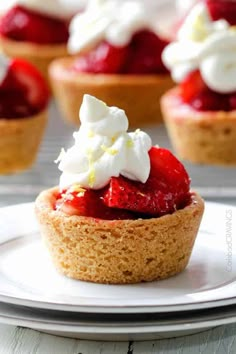 strawberry shortcakes topped with whipped cream and strawberries are on a white plate