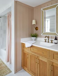 a bathroom with pink walls and wooden cabinets