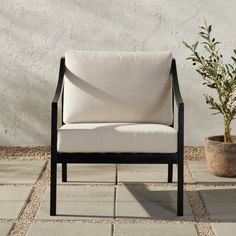 a chair sitting next to a potted plant on top of a stone floored patio