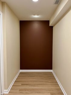 an empty hallway with hard wood floors and brown walls