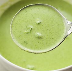 a spoon full of broccoli soup in a white bowl