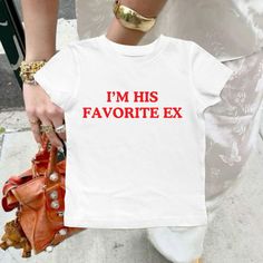 "IM HIS FAVORITE EX" in red on our classic baby tee ♡ Perfect funny gift for yourself or anyone in your life :)  This lightweight baby tee is perfect for everyday wear! ♡DTG Design ♡ 100% Airlume and Ringspun Cotton ♡ Washer & Dryer Safe CARE/ WASH ♡Machine wash: warm (max 40C or 105F); Non-chlorine: bleach as needed; Tumble dry: medium heat; Iron, steam or dry: low heat; Do not dry clean. SIZING ♡ Please check the sizing guide listing photo before purchasing SHIPPING ♡ Each of our items are made with love for each of our buyers. Items will ship in 1-7 business days NOTES ♡ PLEASE MAKE SURE THAT YOU HAVE ENTERED TO CORRECT SIZE, COLOR, AND SHIPPING ADDRESS BEFORE PLACING YOUR ORDER! While it is common to make mistakes and ask for changes, I can not always guarantee that these changes will Funny Baby Tees Women, Baby Tee Sayings, Baby Tee Funny, Funny Baby Tees Y2k, Iconic Shirts, Breakup Gift, Minimal Shirt Design, Funny Baby Tees, Nyc Shirt