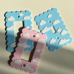 two blue and pink frames sitting next to each other on a white surface with clouds painted on them