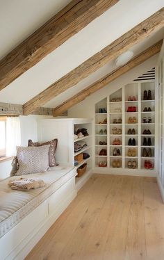 an attic bedroom with white walls and wooden flooring, built in shelving units