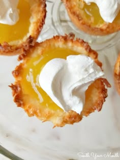 small desserts with whipped cream on them sitting in a glass dish, ready to be eaten