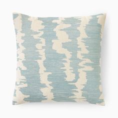 a blue and white pillow with an abstract pattern on the front, sitting against a white background