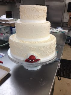 a three tiered white cake with a spiderman on the top is ready to be cut