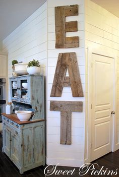 the letters are made out of wood on the wall above the stove top in this kitchen