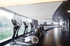 there are many treadmills in the room with glass walls and floor to ceiling windows