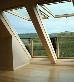 an empty room with large windows and wooden flooring, overlooking the rolling hills in the distance