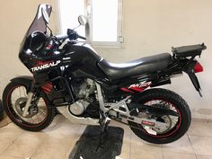 a motorcycle is parked in a room with tile flooring and white walls behind it