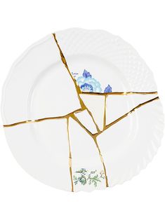 a broken plate with blue flowers on the side and gold foiling around the edges