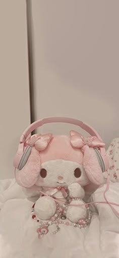 a pink hello kitty purse sitting on top of a bed next to a stuffed animal