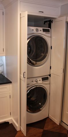 a white washer and dryer in a small room with cabinets on either side