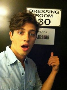 a young man making a funny face in front of a sign that says dressing room 30