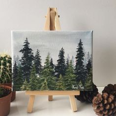 an easel with pine trees painted on it