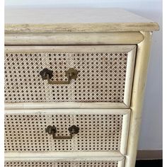 an old white wicker dresser with two drawers and handles on it's sides