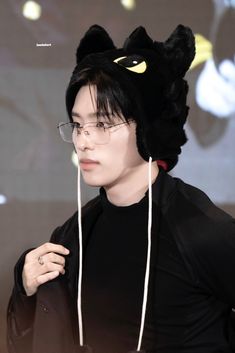 a young man wearing a black cat hat with ears on his head and eye glasses