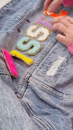 a person with their hand on the back of a pair of jean shorts that have sequins on them