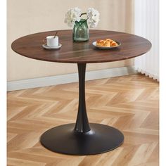 a wooden table with a plate of food on it and flowers in a vase next to it