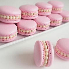 pink macaroons with white pearls are arranged on a tray and ready to be eaten