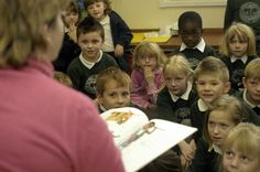 a group of children sitting in front of a teacher