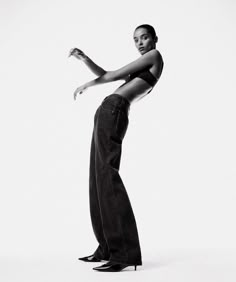 a woman in high heels is posing for a black and white photo with her arms stretched out