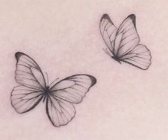 two black and white butterfly tattoos on the back of a woman's shoulder,