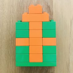 an orange and green lego block sitting on top of a wooden table