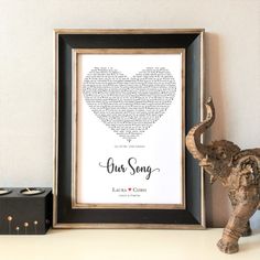 an elephant figurine next to a framed heart with the words our song written in it