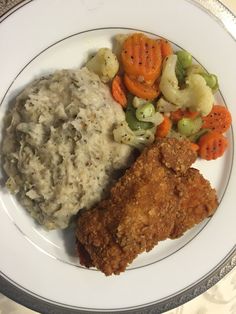 a white plate topped with fried chicken, mashed potatoes and veggies