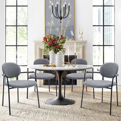 a dining room table with four chairs and a chandelier hanging above it in front of a fireplace