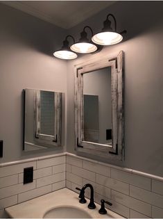 a bathroom sink with two mirrors and lights on it's wall above the sink