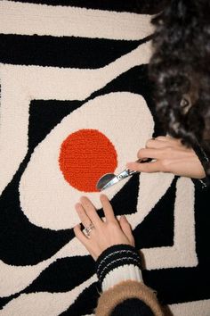 a woman is using scissors to decorate a rug