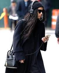 a woman walking down the street while wearing headphones and carrying a black handbag