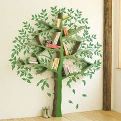 a green tree with books on it in front of a white wall and wooden floor