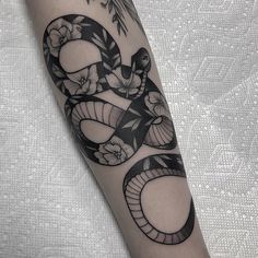 a black and white snake tattoo on the right arm, with flowers around its neck