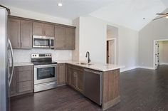 an empty kitchen with stainless steel appliances and wood flooring is pictured in this image