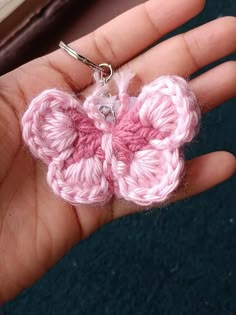 a pink crocheted flower is being held in someone's hand with a metal clip