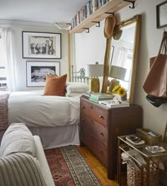 a bed room with a neatly made bed next to a dresser and a mirror on the wall