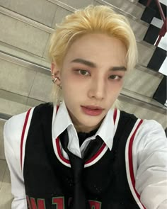 a man with blonde hair wearing a black tie and white shirt is posing for the camera