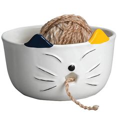 a ball of yarn in a white cat shaped bowl with a rope on the end