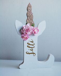 a white wooden letter decorated with pink flowers and a gold glitter topper that says love