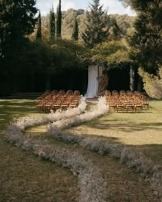 an outdoor ceremony setup with chairs and flowers on the grass, surrounded by trees in the background