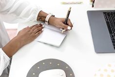 a person sitting at a desk with a notebook and pen in front of a laptop