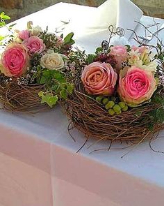 three flowers are placed in a bird's nest on top of a white table